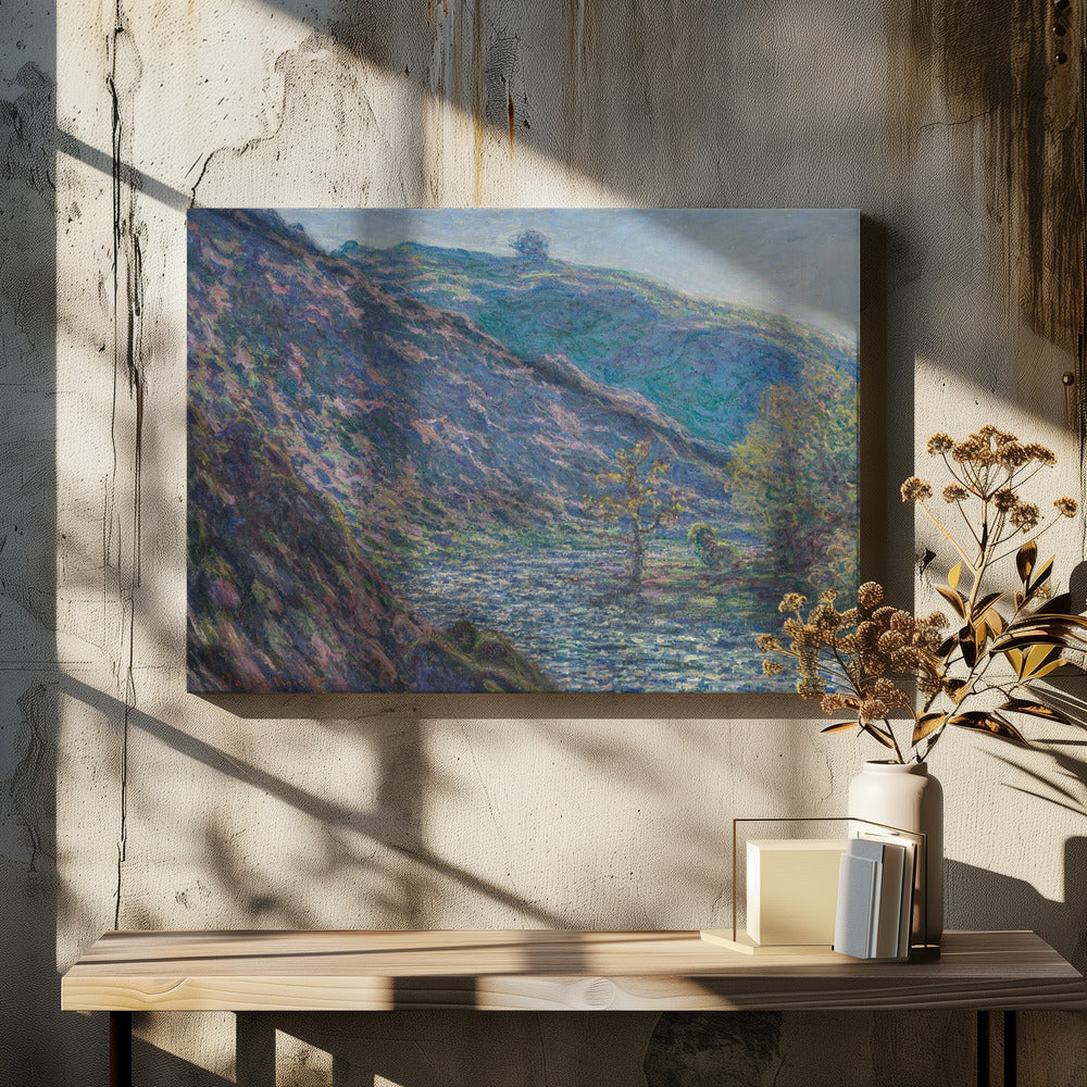 A framed Impressionist painting depicting a river valley. A steep hillside with purple and blue tones dominates the left, while a sun-dappled river flows below. In the distance, gentle green and blue hills rise against a pale sky. Artwork
