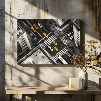 An aerial, black and white photograph of a bustling New York City intersection, with the iconic yellow taxi cabs highlighted in a vibrant selective color. Pedestrians cross the street as cars and a bus navigate the busy roads between tall buildings. Wall Art