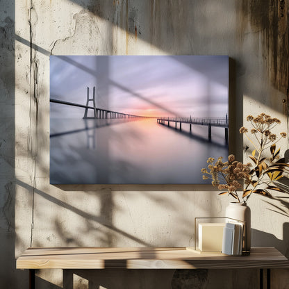 A serene long-exposure photograph of a modern cable-stayed bridge and a pier stretching over mirror-like water at sunset. The sky is filled with soft, streaky clouds in hues of pink and purple, reflected on the calm water's surface, all enclosed in a silver frame. Decor