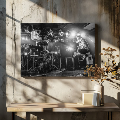 A high-energy, black and white photograph of a rock band performing live. The bassist and guitarist are frozen in mid-air as they jump, while the drummer plays in the background, all under bright stage lights. Print
