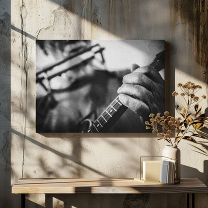A grainy, black and white close-up photograph of a musician's hand gripping the neck of a stringed instrument. The focus is on the hand and the frets, with the musician's body and face softly blurred in the background. The image is enclosed in a silver frame. Wall Art