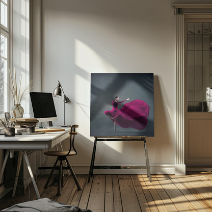 A graceful ballet dancer in a vibrant magenta dress strikes a pose on pointe, with the long, flowing fabric of her skirt billowing out dramatically behind her against a dark, textured gray background, all enclosed in a simple light wood frame. Decor