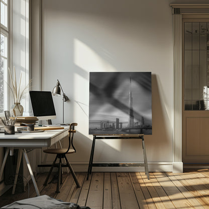 A framed, long-exposure black and white photograph of the Dubai skyline, featuring the iconic Burj Khalifa. The sky has a dramatic, streaky appearance from the long exposure, contrasting with the sharp details of the modern architecture. A bridge crosses the water in the foreground. Print