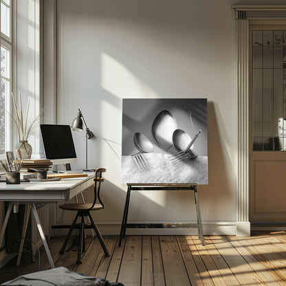 A conceptual black and white photograph in a light wood frame, featuring three spoons standing upright on a white towel, while a fork in the foreground holds a lit, smoking cigarette between its tines. Wall Art