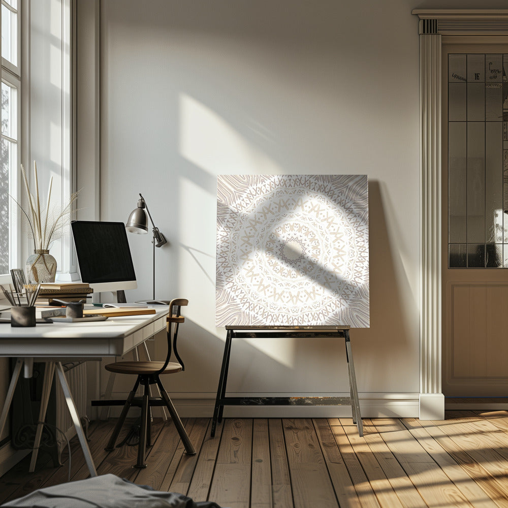 A framed square artwork featuring a detailed mandala design in neutral tones. The intricate pattern consists of concentric circles with geometric shapes like 'X's and chevrons, rendered in shades of beige and taupe on a white background, all enclosed in a light-colored wooden frame. Decor