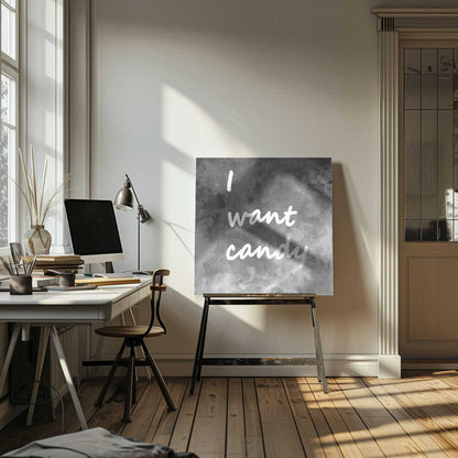 A framed typography art piece with a light brown wood frame. It features the phrase 'I want candy' in a white, handwritten script against a textured, dark gray and white chalkboard-style background. Wall Art