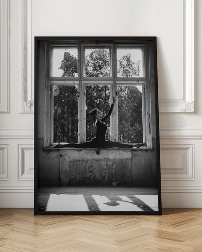 A black and white photograph of a graceful female dancer holding a perfect split on a large, dilapidated windowsill. She is silhouetted against the bright light from the broken window panes, with her arm elegantly raised. The setting is an abandoned room with peeling paint, creating a stark contrast between the dancer's elegance and the decaying environment. Wall Art