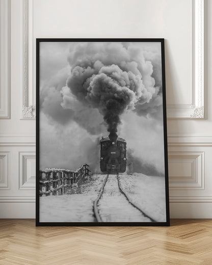 A dramatic black and white photograph of a vintage steam train on tracks in a snowy landscape, viewed from a low angle. A massive, powerful plume of dark smoke billows from the smokestack, filling the sky. Decor