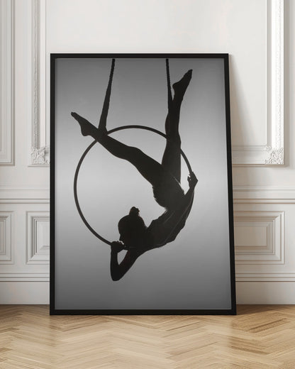 A black silhouette of a graceful female acrobat in an inverted pose on a suspended aerial hoop, set against a light grey background. Print