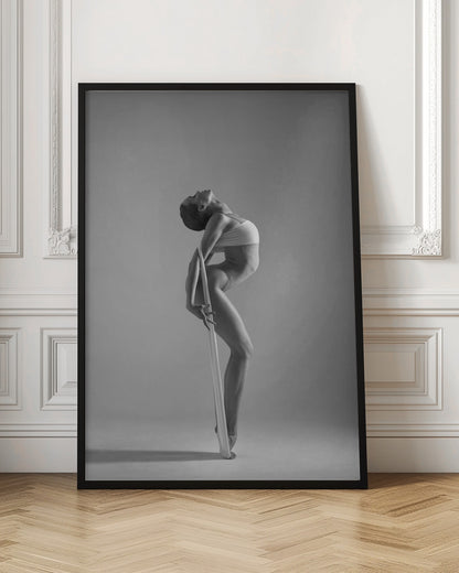 A framed black and white photograph of a graceful female dancer arching her back dramatically. She holds a long white elastic band that stretches down her body to her foot, emphasizing her athletic form and flexibility against a plain studio background. Print