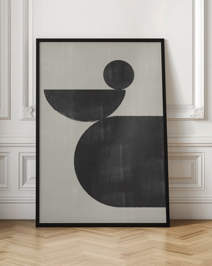 A minimalist abstract artwork featuring three charcoal black shapes stacked against a light beige textured background. At the bottom is a large, rounded shape, on which a semi-circle is balanced. A smaller, full circle rests on top of the semi-circle, creating a sense of precarious balance. The piece is enclosed in a simple black frame. Decor