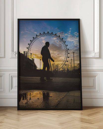 A low-angle shot of a person's silhouette walking past the London Eye at sunset, with the vibrant orange and blue sky reflected in a puddle in the foreground. Decor