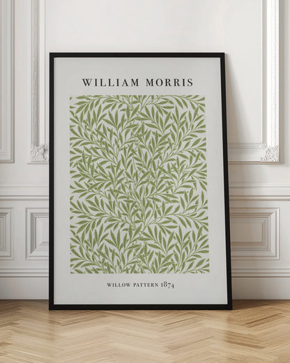 A framed art print of William Morris's 'Willow Pattern 1874'. The print features an intricate, repeating pattern of green willow branches and leaves on an off-white background, with the artist's name and pattern title in black text above and below the design. Print