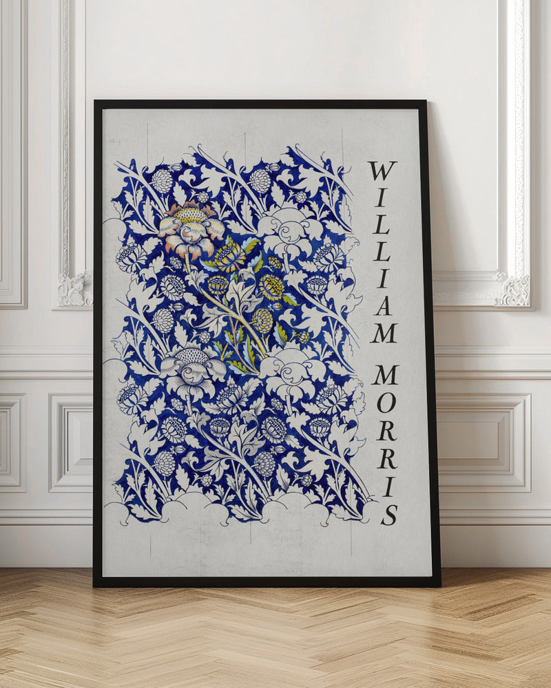 A vintage art print by William Morris featuring an intricate blue and white floral pattern on a light gray, textured background. The design swatch shows stylized flowers and acanthus leaves, with some central flowers highlighted in yellow and peach. The name 'WILLIAM MORRIS' is printed vertically in a black serif font along the right edge. The print is displayed in a thin black frame. Decor