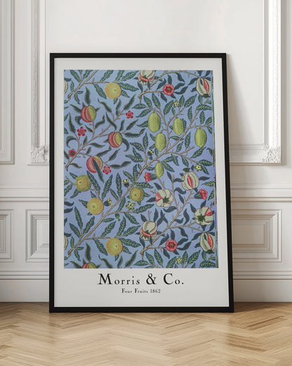 A framed art print of the 'Four Fruits 1862' pattern by Morris & Co. The intricate botanical design features various fruits like lemons, pomegranates, and oranges, along with red and yellow flowers, all intertwined on branches with dark green leaves against a light blue background. Poster