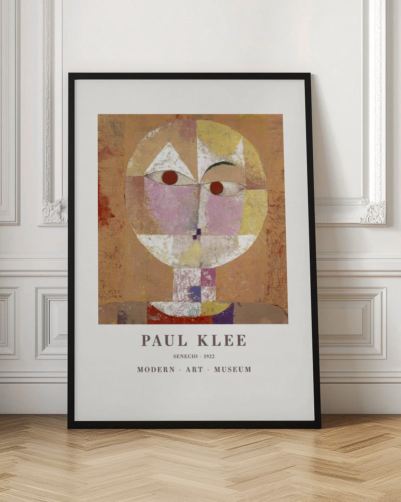 A framed museum poster of Paul Klee's 1922 painting 'Senecio'. The artwork is an abstract, geometric portrait of a human head in warm tones of orange, yellow, pink, and red against a textured brown background. The text 'PAUL KLEE', 'SENECIO - 1922', and 'MODERN - ART - MUSEUM' is printed below the image. Print
