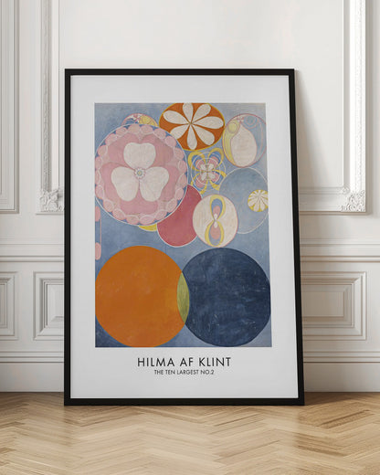 A poster of Hilma af Klint's abstract painting 'The Ten Largest, No. 2'. The artwork features a variety of colorful circles and floral-like motifs on a light blue background, with dominant colors of pink, orange, and dark blue. The artist's name and artwork title are printed below. Artwork