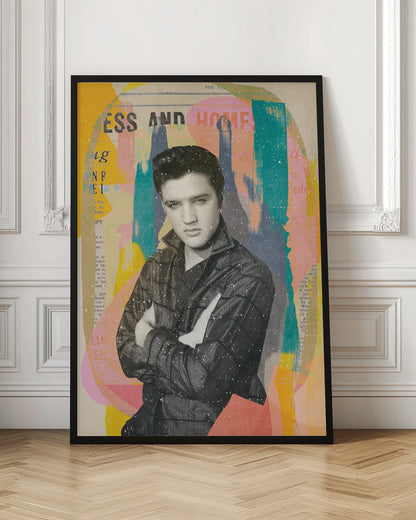 A pop art style collage of a young Elvis Presley. The portrait is in black and white, showing him with his arms crossed and a serious expression. The background is an abstract mix of colorful shapes in yellow, teal, orange, and pink, with fragments of newspaper text visible. The entire piece is covered in a light white speckle effect and is shown in a black frame. Print