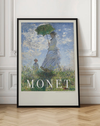 A vintage art poster of Claude Monet's impressionist painting, 'Woman with a Parasol - Madame Monet and Her Son.' It depicts a woman in a white dress holding a green parasol on a grassy hill against a blue, cloud-filled sky, with her son visible in the background. The text 'MONET' is prominently displayed at the bottom. Wall Art