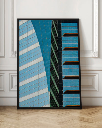 An abstract close-up photograph of modern skyscrapers, featuring a dynamic composition of intersecting lines and geometric patterns. The facades consist of blue, white, and dark green reflective glass, creating a visually complex play of light, shadow, and color. Wall Art