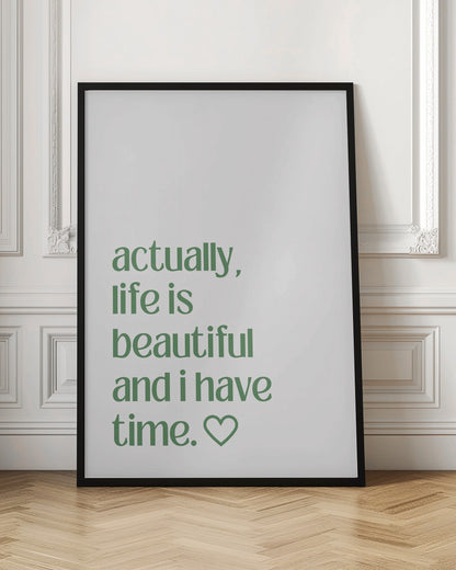 A framed poster with a white background and a black frame. The poster features text in a green, lowercase, sans-serif font that reads, 'actually, life is beautiful and i have time.' followed by an outlined heart symbol. Decor