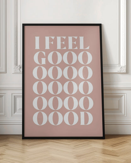A framed typographic poster featuring the words 'I FEEL GOOOOOD' in a large, white serif font against a dusty pink background. The word 'GOOD' is stylized and stretched vertically with multiple rows of the letter 'O'. Artwork