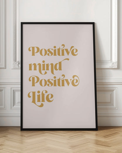 A framed art print featuring the motivational quote 'Positive mind Positive life' in a gold, retro-style font against a light pink background. The text is centered and arranged vertically. Artwork