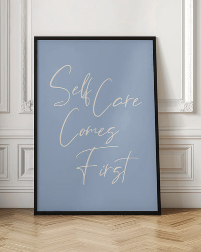 A framed poster featuring the phrase 'Self Care Comes First' in an elegant, off-white cursive font against a solid light blue background. The artwork is enclosed in a simple black frame. Decor