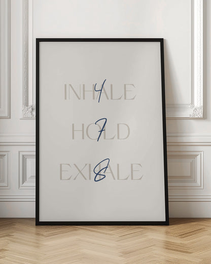 A minimalist framed art print with a cream background. It features the words 'INHALE', 'HOLD', and 'EXHALE' stacked vertically in a light beige serif font. Superimposed over these words are the numbers '4', '7', and '8' respectively, written in a dark blue cursive script, referencing the 4-7-8 breathing technique for relaxation. Wall Art
