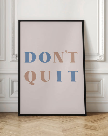 A minimalist motivational art print with a pale pink background and a thin black frame. The text reads 'DON'T QUIT' in a large serif font, with the words 'DO' and 'IT' highlighted in blue and the words 'N'T' and 'QU' in a muted terracotta color, creating a hidden 'DO IT' message. Decor