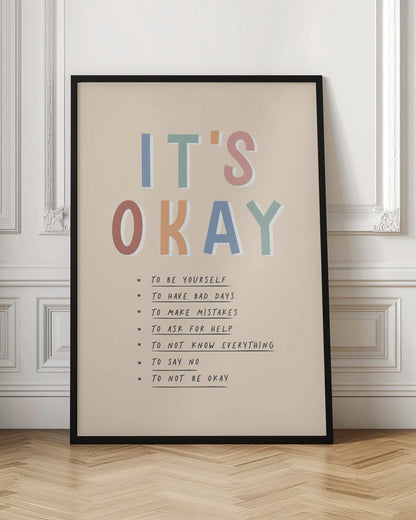 An inspirational framed poster with the words 'IT'S OKAY' in large, colorful letters. Below is a list of affirmations including 'TO BE YOURSELF', 'TO HAVE BAD DAYS', and 'TO MAKE MISTAKES' on a beige background. Artwork