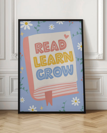 A cheerful illustration of an open book with the words 'READ LEARN GROW' written in colorful, playful letters. The background is light blue with white daisies, green vines, and yellow sparkles, creating a positive and educational theme. Poster