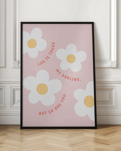 A motivational art print with a light pink background featuring four simple, stylized white daisies with yellow centers. The quote 'Life is tough my darling, but so are you.' is written in a playful, reddish-orange handwritten font that curves around the flowers. Artwork