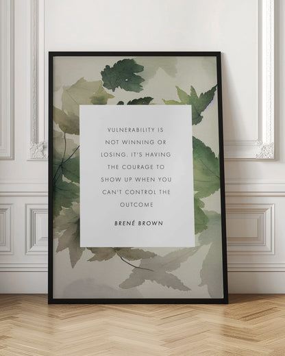 A framed art print featuring an inspirational quote by Brené Brown. The quote, 'Vulnerability is not winning or losing. It's having the courage to show up when you can't control the outcome,' is printed in black uppercase letters on a central white rectangle. The background consists of a soft watercolor illustration of green and beige leaves. The piece is enclosed in a simple black frame. Wall Art