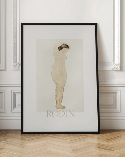 A framed art print of a sketch by Auguste Rodin. The drawing features a standing nude woman in profile with her arms raised behind her head. The artwork is done in a minimalist style with brown outlines and a light beige watercolor wash on an off-white background, with the name 'RODIN' printed below. The print is surrounded by a white mat and a simple black frame. Decor
