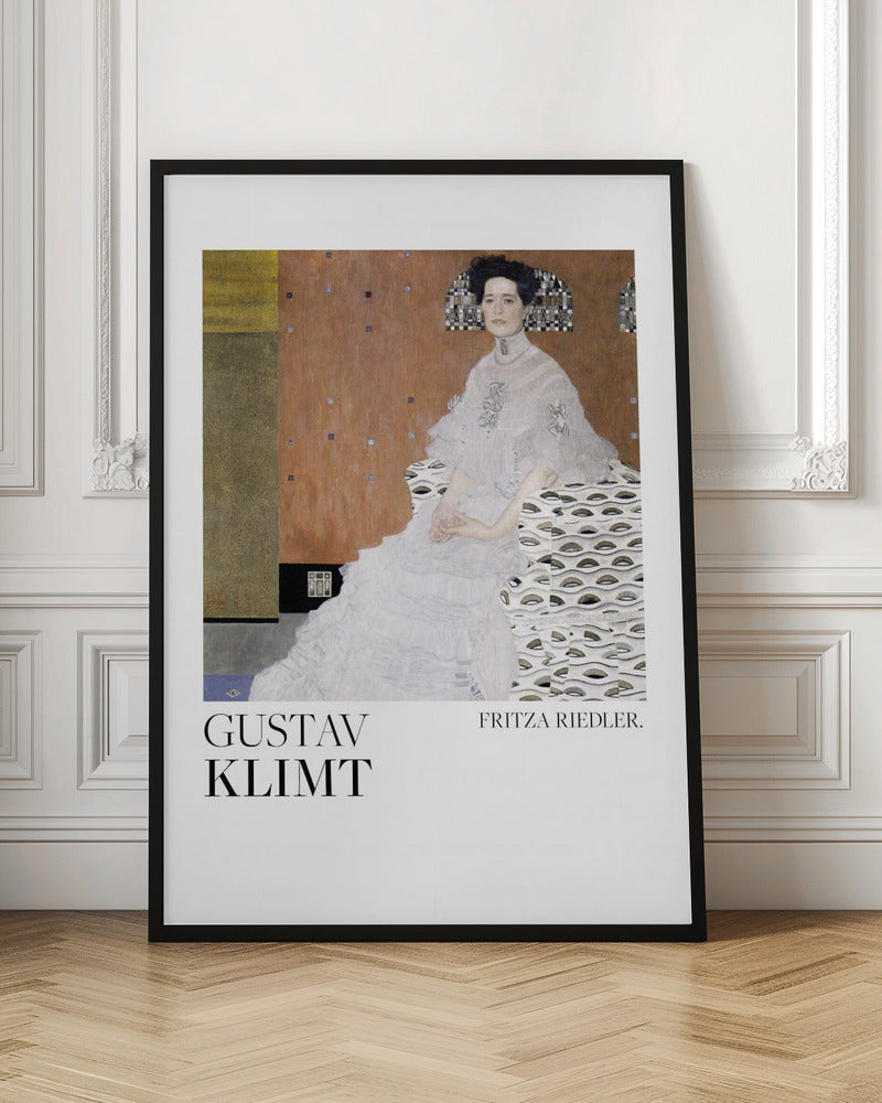 A framed art print of Gustav Klimt's 1906 painting, 'Portrait of Fritza Riedler'. A woman with dark, upswept hair wearing a detailed, high-necked white gown sits in a patterned chair against a warm, textured brown and gold background. Below the artwork, on a white border, the text 'GUSTAV KLIMT' and 'FRITZA RIEDLER.' is printed. Print
