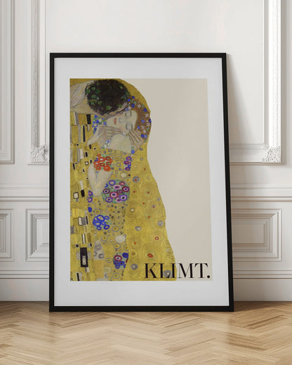 A framed art print of Gustav Klimt's 'The Kiss'. A couple embraces in ornate golden robes against a shimmering gold background. The poster includes the artist's name 'KLIMT.' in the lower right. Decor