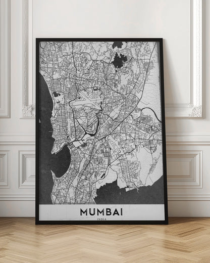 A minimalist black and white framed map of Mumbai. The city's intricate road network is depicted in black lines on a white background, with surrounding water bodies shown in a textured dark grey. The name 'MUMBAI' is in bold, uppercase letters at the bottom. Print