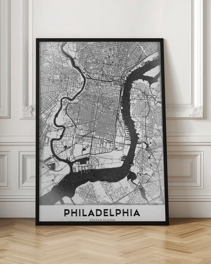 A modern black and white framed poster of a city map of Philadelphia. The map details the street grid, with the Schuylkill and Delaware rivers prominently featured in solid black. The word 'PHILADELPHIA' is printed in a bold, black sans-serif font at the bottom. Artwork