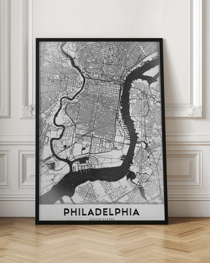 A modern black and white framed poster of a city map of Philadelphia. The map details the street grid, with the Schuylkill and Delaware rivers prominently featured in solid black. The word 'PHILADELPHIA' is printed in a bold, black sans-serif font at the bottom. Artwork