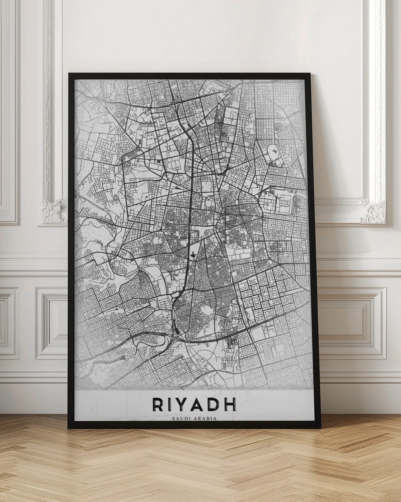 A minimalist, black and white framed poster of a city map of Riyadh. The map details the intricate network of streets and city blocks in black lines on a textured, light gray background. At the bottom, the word 'RIYADH' is printed in a bold, black, sans-serif font. Wall Art