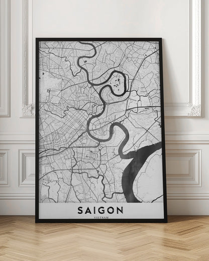 A minimalist black and white map poster of Saigon, Vietnam, displayed in a black frame. The map highlights the winding Saigon River in solid black against a white background with a complex grid of roads and smaller waterways in thin black lines. At the bottom, a white border contains the word 'SAIGON' in bold, black, capital letters. Wall Art