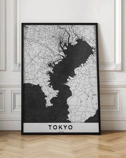 A minimalist black and white map of Tokyo, Japan, in a black frame. The map shows the city's road network in thin black lines on a white background, while Tokyo Bay and other water bodies are depicted in solid black. A white banner at the bottom contains the word 'TOKYO' in a clean, sans-serif font. Wall Art