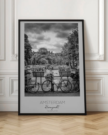 A black and white poster of the Herengracht canal in Amsterdam. In the foreground, two bicycles are parked by a railing with flower boxes. In the background, there's a classic view of the canal with a bridge, canal houses, and boats under a cloudy sky. The bottom of the poster has text that reads 'AMSTERDAM Herengracht NEDERLAND'. Decor