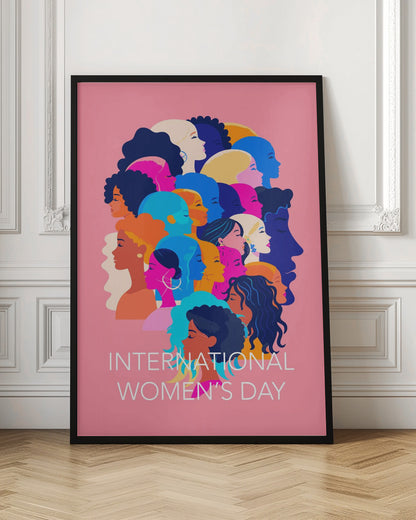 A vibrant poster for International Women's Day featuring a pink background. The central graphic is a collage of colorful profiles of diverse women, representing different ethnicities and hairstyles, all looking in the same direction. Below the illustration, white text reads 'INTERNATIONAL WOMEN'S DAY'. Wall Art