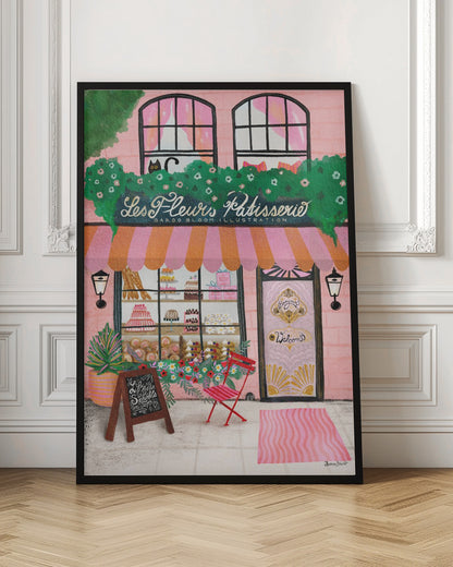 A whimsical illustration of a charming pink French bakery named 'Les Fleurs Patisserie'. A pink and orange striped awning hangs over a window filled with cakes and pastries. A black cat peeks out from a lush green garland above the shop. In front, a small red chair, a chalkboard sign, and an ornate pink door add to the inviting Parisian scene. Print