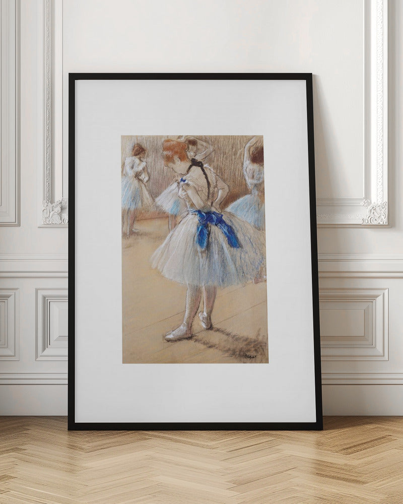 A framed print of an impressionist pastel drawing by Edgar Degas. It shows a ballerina in a white and light blue tutu with a prominent royal blue sash. She is viewed from the side as she adjusts her costume, with other dancers blurred in the background of a dance studio. Poster