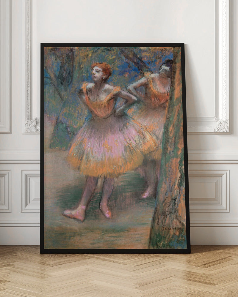 An impressionist pastel painting by Edgar Degas titled 'Dancers in Pink and Orange.' It depicts two ballerinas backstage. The dancer in the foreground has red hair, wears a pink and orange tutu, and stands with her hands on her hips, looking off to the side. A second dancer is partially visible behind her. The background is a textured blend of blues, greens, and browns. Artwork