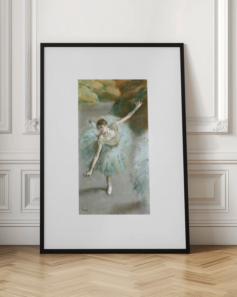 A framed vertical reproduction of an Edgar Degas painting showing a ballerina from a high angle. She wears a voluminous light blue tutu and is posed gracefully with arms outstretched against a soft, impressionistic background of earthy browns and tans. Poster