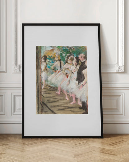 An Impressionist painting by Edgar Degas showing a group of ballet dancers in white tutus waiting in the wings of a stage. A man in a dark suit stands with them. The artwork is presented in a black frame with a white mat. Print